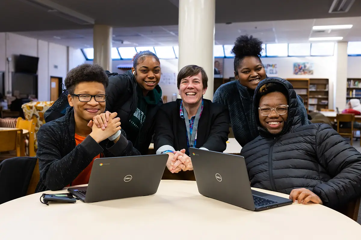 An instructor in the writing center poses for a group photo with four students