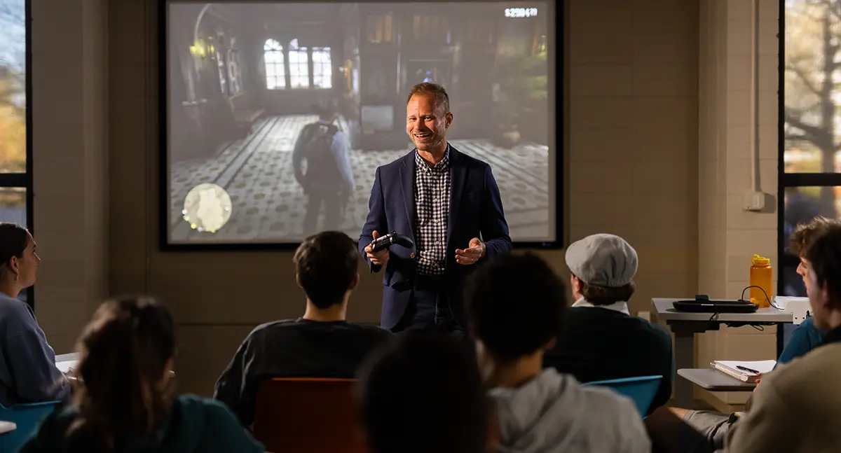 Tore Olssen teaching a class on Red Dead Redemption with a gameplay still on the screen behind him