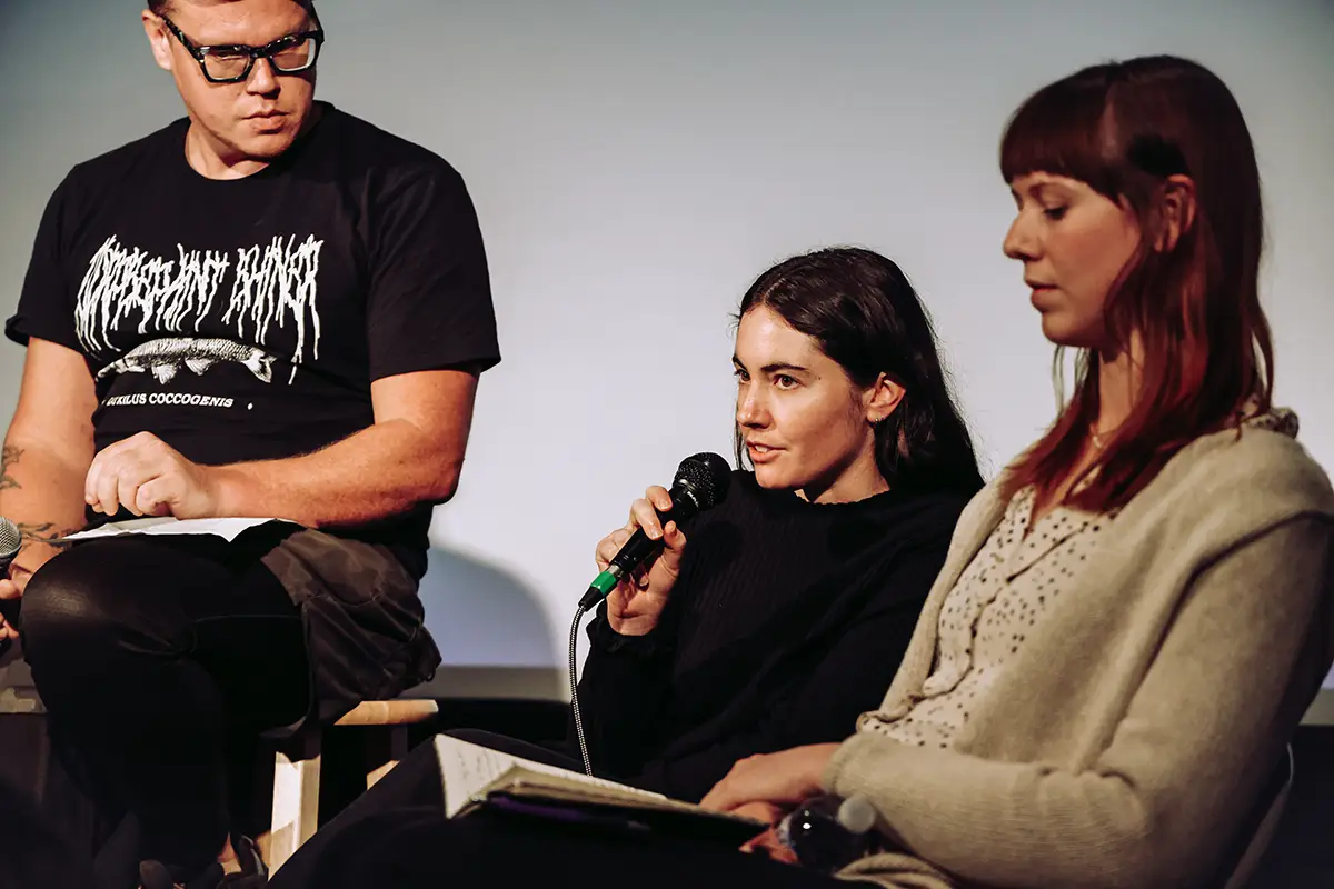 A woman speaks into a microphone as part of an on-stage panel