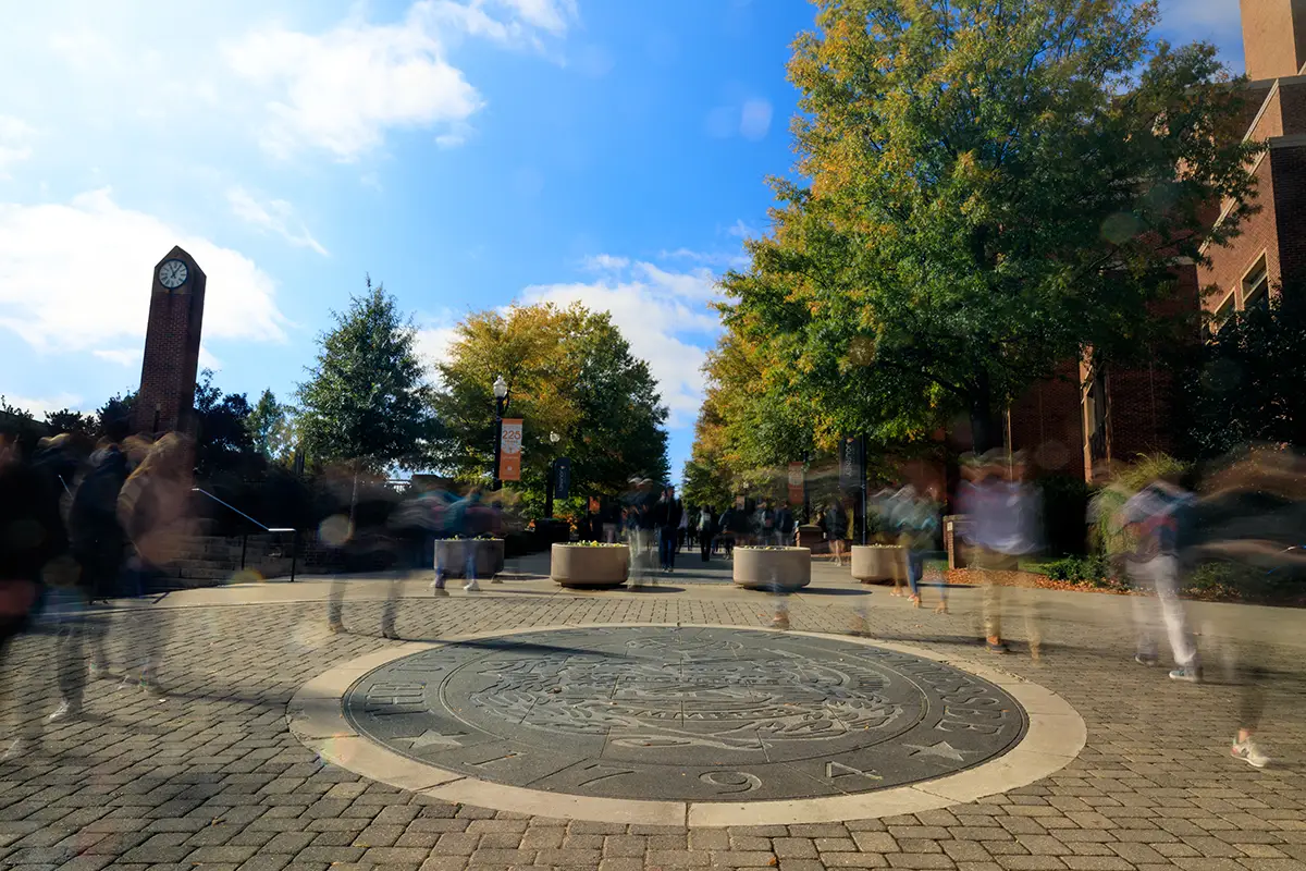 Timelapse photo of students walking past the University seal in front of the undergraduate library. Photo by Steven Bridges