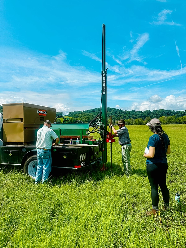 Three people looking at scientific equipment on a truck