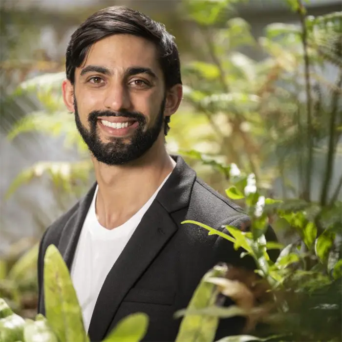 headshot photo of a man surrounded by greenery